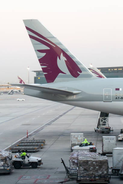 Doha, Qatar: The tail (aircraft vertical stabilizer) of a Qatar Airways Boeing 777-300ER parked at a gate during the morning \