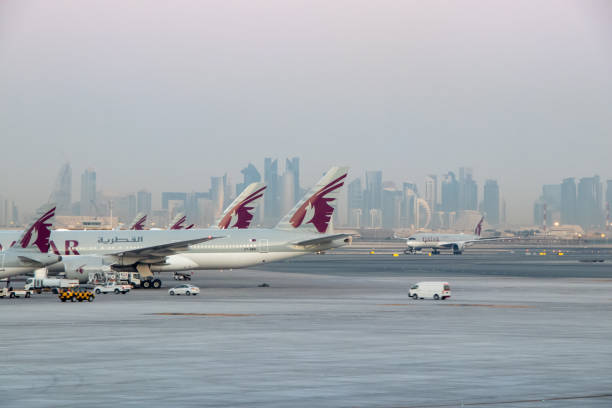 qatar airways aircraft parked at remote stands with doha skyline in distance - cockpit airplane commercial airplane boeing stock-fotos und bilder