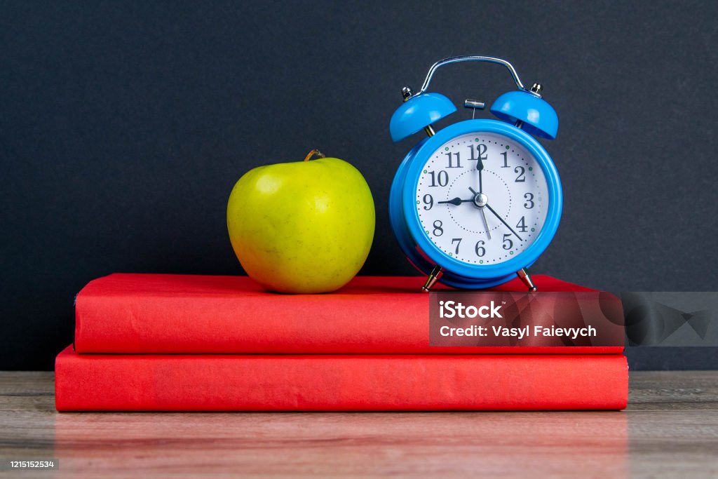 Blue watch and green apple stand on red books Blue watch and green apple stand on red books. Adult Stock Photo