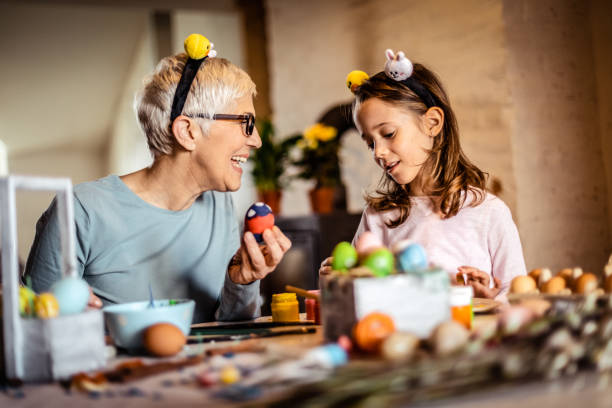 istock Grandmother with granddaughter decorating Easter eggs at home. 1215152581