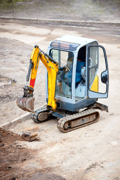 istock Tracked mini excavator breaks out old curbs before installing new curbs. The concept of using economical and compact equipment 1215154009