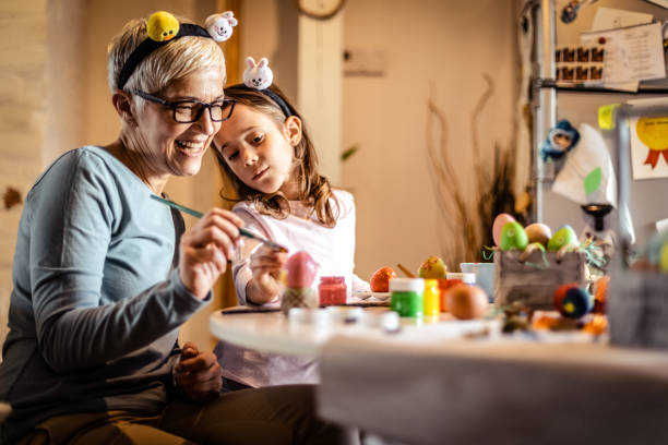 istock Grandmother with granddaughter decorating Easter eggs at home. 1215154117