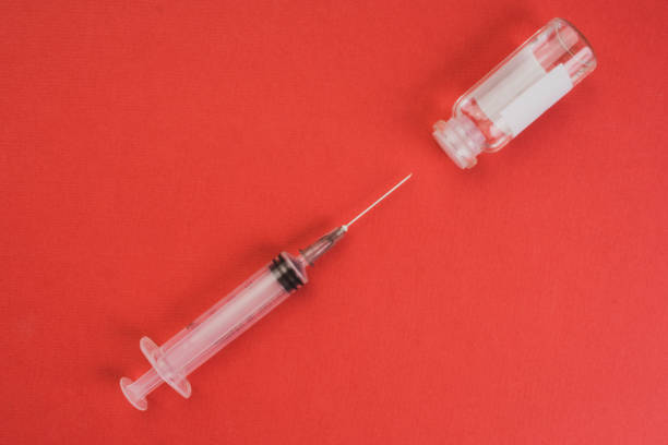 istock medical ampoules and syringe on red background 1215154596
