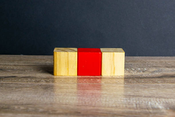 istock Three wooden cubes stand on a wooden table, two with which white one is red 1215154708