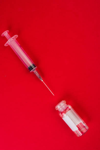 istock medical ampoules and syringe on red background 1215154788