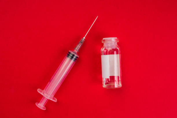 istock medical ampoules and syringe on red background 1215154829