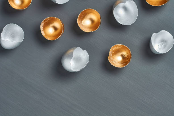 istock Silver and golden egg shells on dark concrete background. Concept of easter, pricelless ideas, successful business investment or luxury breakfast. Copy space. Top view 1215157909
