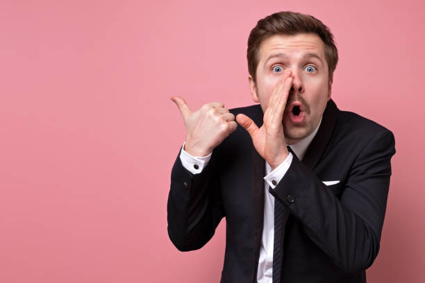 Secret, gossip concept. Young man whispering a secret Secret, gossip concept. Young man whispering a secret isolated on trendy pink studio background. Human emotions, facial expression concept. whisper men stock pictures, royalty-free photos & images