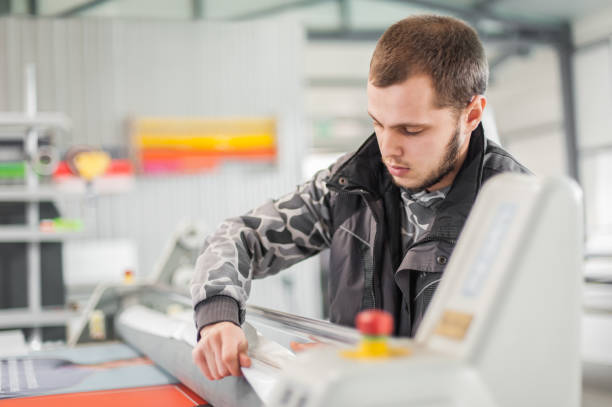 istock Technician glue poster to foam with semi automatic gluing machine 1215161053