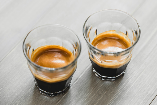 Double shot Espresso coffee in the glasses on vintage wood table background