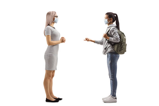 Two young women with protective medical masks having a conversation Full length profile shot of a two young women with protective medical masks having a conversation isolated on white background body talk stock pictures, royalty-free photos & images