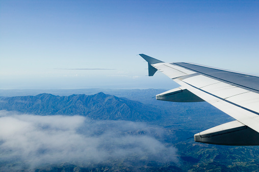 Mountain peaks and plane wing seen from plane - stock photo