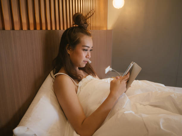 istock Young woman using a mobile phone in her bed at home 1215168475