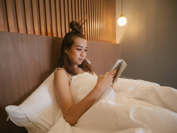 istock Young woman using a mobile phone in her bed at home 1215168518