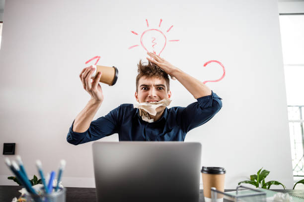 Young businessman discussing work with a coworker while sitting at a table during a meeting in an office