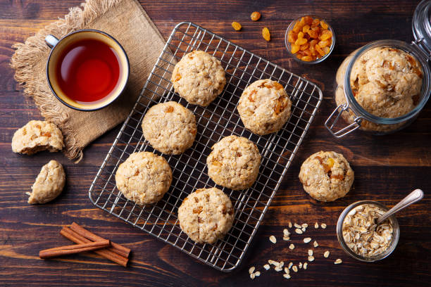 biscoitos veganos de aveia no rack de resfriamento com xícara de chá. fundo de madeira. vista superior. - vegetable baked cake cup - fotografias e filmes do acervo