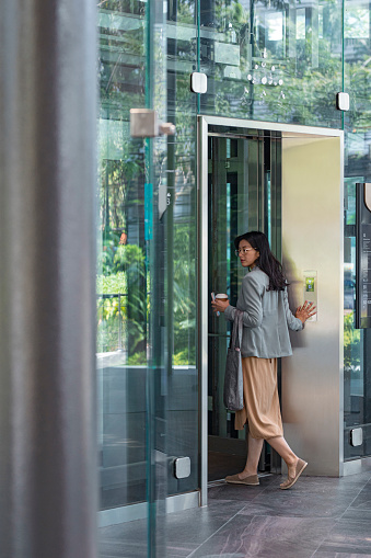 Asian businesswoman entering an elevator in an office building.