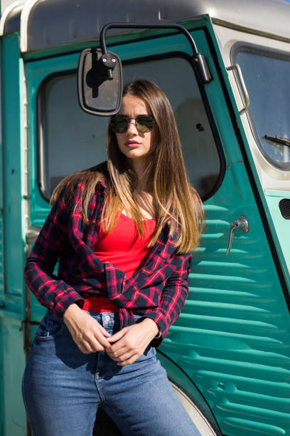 istock Smiling young woman by the vintage minivan 1215176101