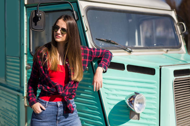 istock Smiling young woman by the vintage minivan 1215176124