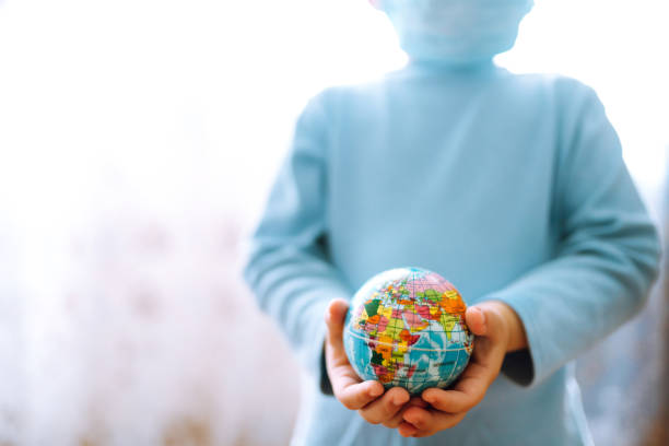 istock Child in protective sterile medical mask holding a world globe. 1215176771