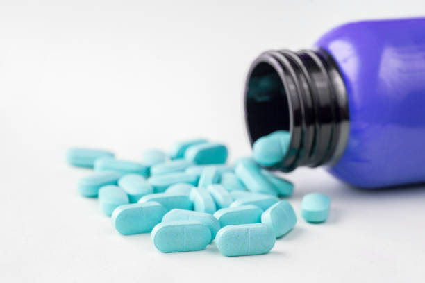 tampas de medicina de cor azul derramando fora da garrafa - chinese medicine nutritional supplement herb pill - fotografias e filmes do acervo