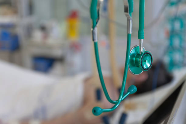 Green stethoscope, on background patient  connected to medical ventilator in ICU in hospital, a place where can be treated patients with pneumonia caused by coronavirus covid 19. stock photo