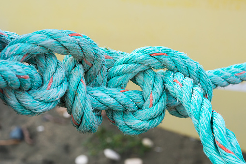 Old green rope knotted on a yellow background. Knot. Insoluble problem concept