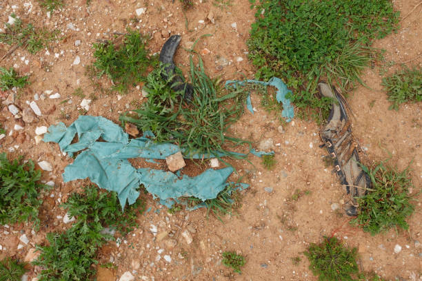 Plastic bags old shoe and other debris buried in landfill ground.