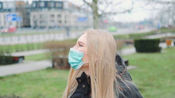 istock Young female feeling saved by putting on face medical mask 1215184741
