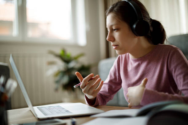 teenager-mädchen mit kopfhörern, das online-schulunterricht zu hause hat - studium online stock-fotos und bilder