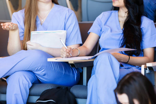 istock Unrecognizable female students, wearing scrubs, chat in class 1215187901