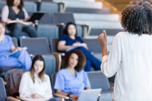 istock Unrecognizable teacher gestures as she lectures a class of students. 1215188711