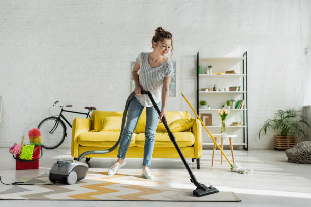 felice ragazza pulire tappeto con aspirapolvere - carpet caucasian domestic room home interior foto e immagini stock