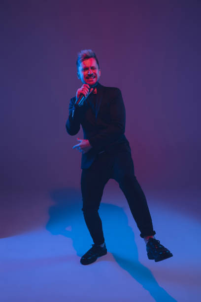 istock Young caucasian musician, performer singing, dancing in neon light on gradient background 1215190075