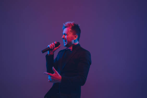 istock Young caucasian musician, performer singing, dancing in neon light on gradient background 1215190087