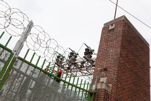 istock Angled view of power substation enclosure with old brick and wrought iron security enhanced with modern razor wire 1215191272