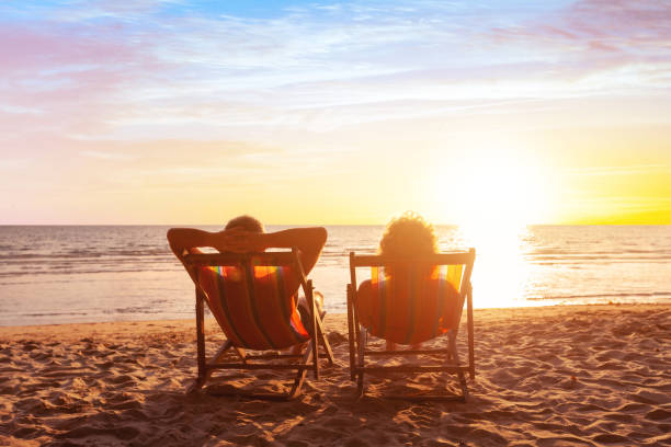 summer holidays, beach travel, vacation for couple summer holidays, beach travel, vacation for couple, man and woman relax and enjoy life together at sunset deck chair stock pictures, royalty-free photos & images