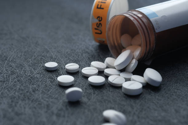 istock White pills spilling on black background, close up 1215192427