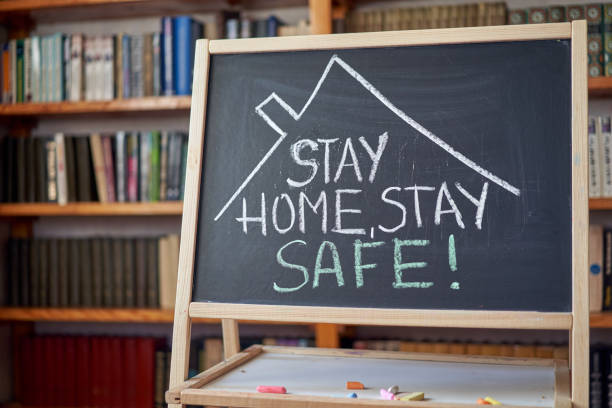 istock inscription stay at home. Outbreak Warning. written white chalk on blackboard in connection with epidemic of coronavirus worldwide. 1215198431