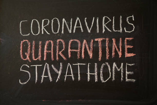 istock inscription stay at home. Outbreak Warning. written white chalk on blackboard in connection with epidemic of coronavirus worldwide. 1215198450