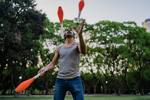 Argentinian mature man juggling with cones in public park. Puerto Madero, Buenos Aires, Argentina.