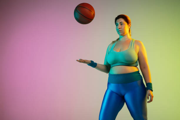 istock Young caucasian plus size female model's training on gradient purple green background 1215203380