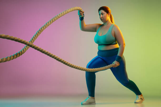 istock Young caucasian plus size female model's training on gradient purple green background 1215203388