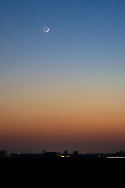 Crescent moon and stunning colors in the evening sky over the dutch landscape.