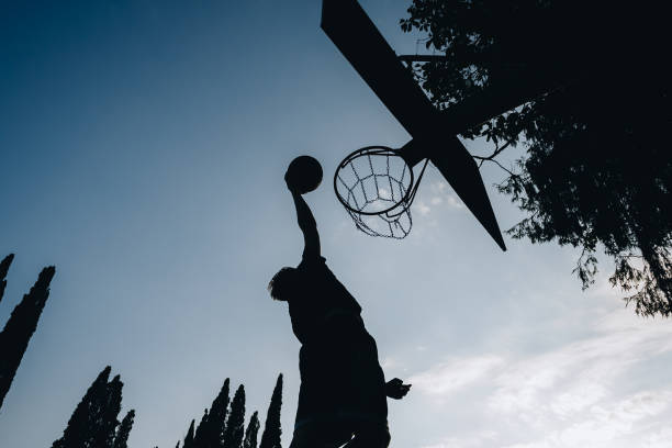 istock streetball Basketball player performs a slam dunk 1215205144