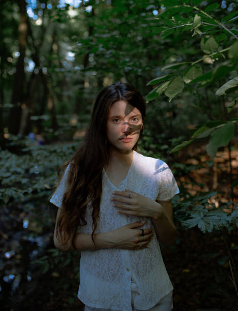 istock Young beautiful woman standing in shadows in forest 1215207419