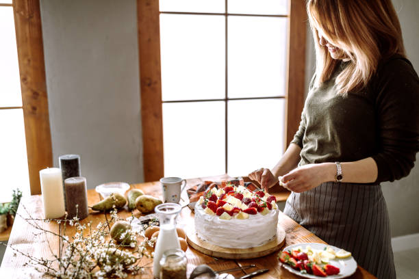 istock Woman Decorating Cake With Lemon, Lime And Strawberries 1215221027
