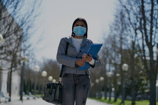 istock Girl putting on a protective mask to avoid contagion while walking down the street. Coronavirus concept 1215227519