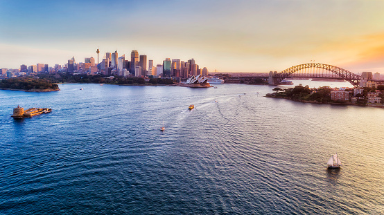 Sydney harbour at sunset around major city landmarks from Fort Denison to the Sydney harbour bridge in elevated aerial view.