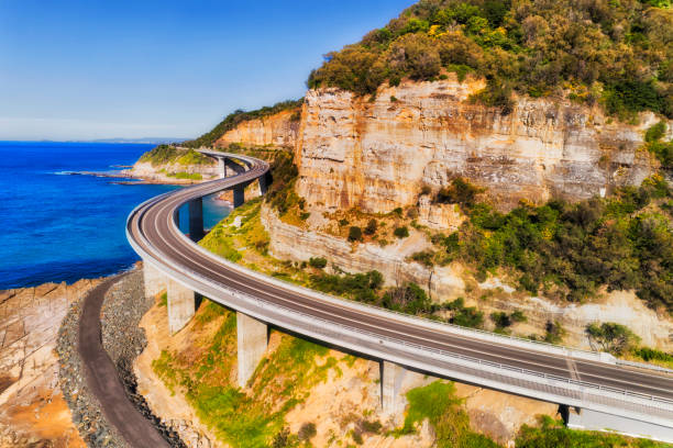 D GPD Bridge arc to south Elevated winding road of Grand Pacific Drive as Sea cliff bridge from Sydney to Wollongong - aerial view on a sunny day. steep photos stock pictures, royalty-free photos & images